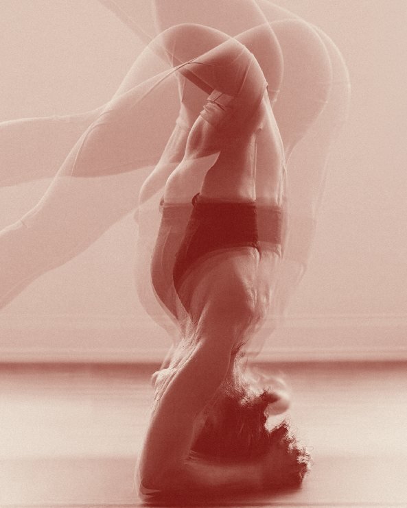 Mujer en postura invertida durante una clase de hot yoga FLWW
